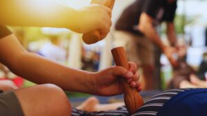 Praticien utilisant le maillet et le stick en bois lors d’un massage Tok Sen, dans un contexte de formation avancée